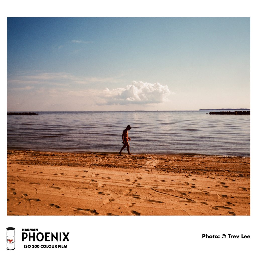 Image of a person walking on a beach on a sunny day - shot on HARMAN Phoenix 120 film by Trev Lee